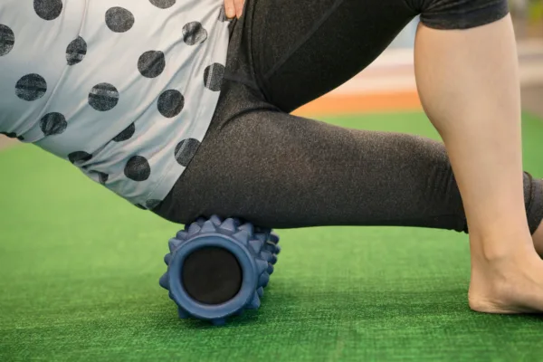 Female using a foam roller on her leg to release tension and help with muscle pain in the exercise class