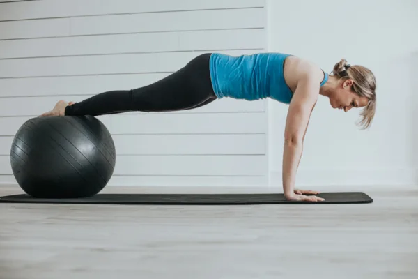 How to use the stability ball - A female balancing with her feet on a ball with hands on the floor