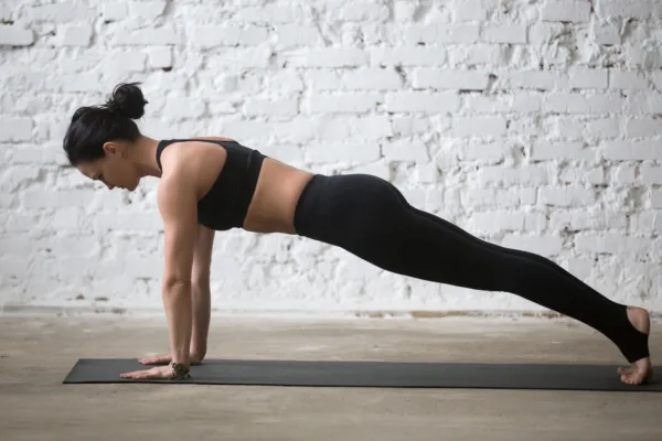 How to use the stability ball - Woman practicing yoga concept, standing in Push ups, press ups exercise, phalankasana, Plank pose, working out wearing black sportswear, full length, white loft background