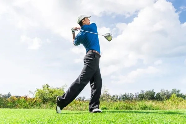 Male golfer in blue t-shirt taking a shot