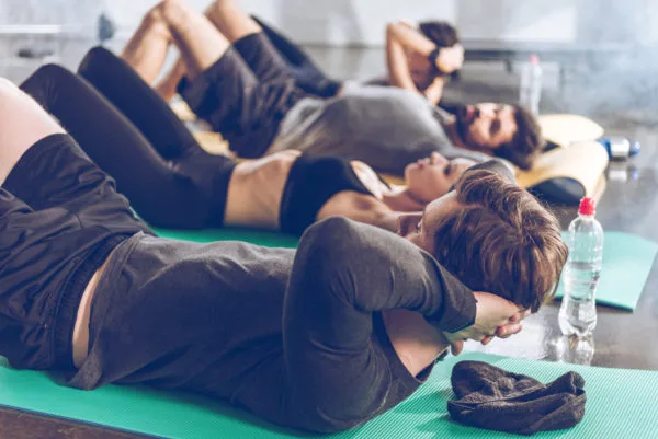 Exercise and cancer - A group of people lying on their backs on exercise mats wearing gym clothes