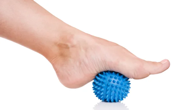 Pilates exercise balls - Woman's foot with spiny plastic blue massage ball isolated on white background