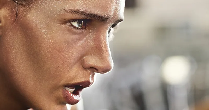 Pilates Principles - Concentration - A close up of a woman's face, side on. The woman is sweating and looks serious.