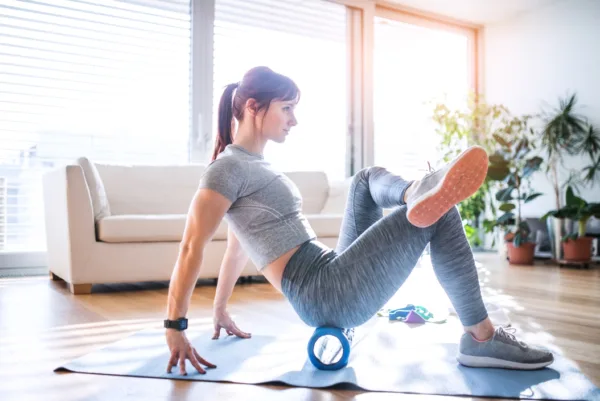 Foam rolling - A female in a studio sitting on a foam roller on the floor 