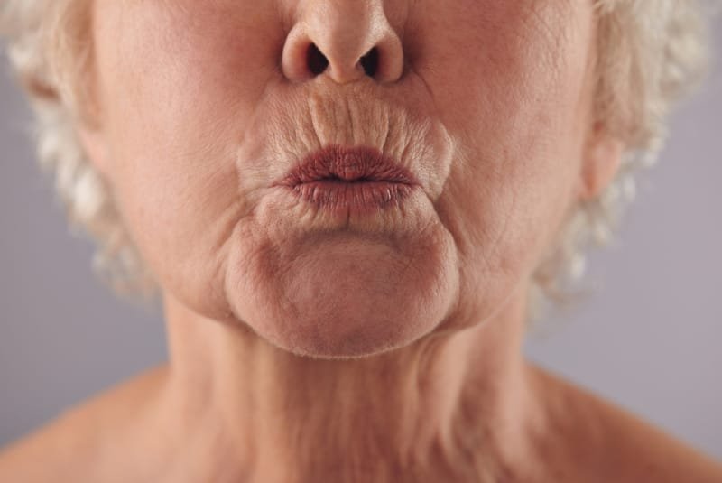 COPD - A close up shot of an elderly woman's face just the lower half. She is pursing her lips.