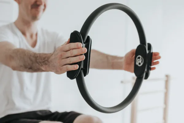 male holding a pilates wheel to perform an exercise