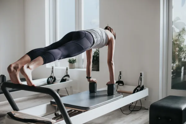 a female balancing on her hands utilising a reformer machine