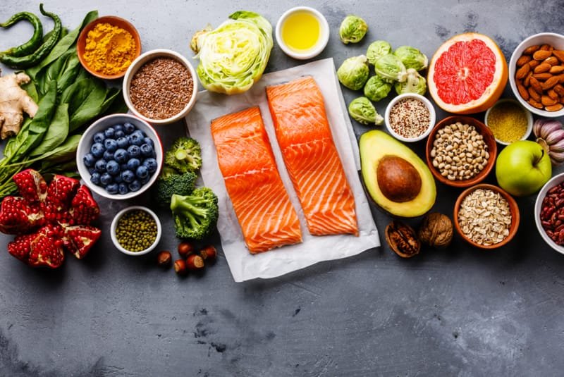 World osteoporosis day - An overhead shot of fresh fruit, pulses, seeds and vegetables surrounding two darnes of Salmon on grease-proof paper.