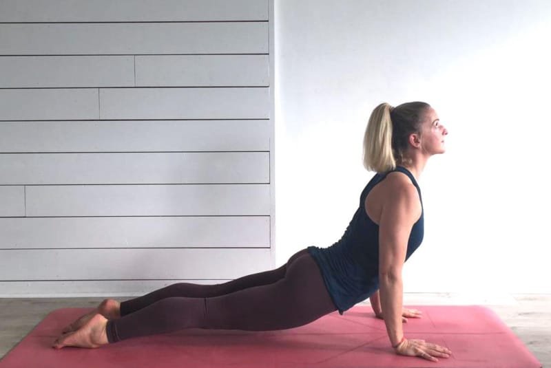 Yoga advantages - A woman performing an 'updog' yoga pose on a red mat in a studio