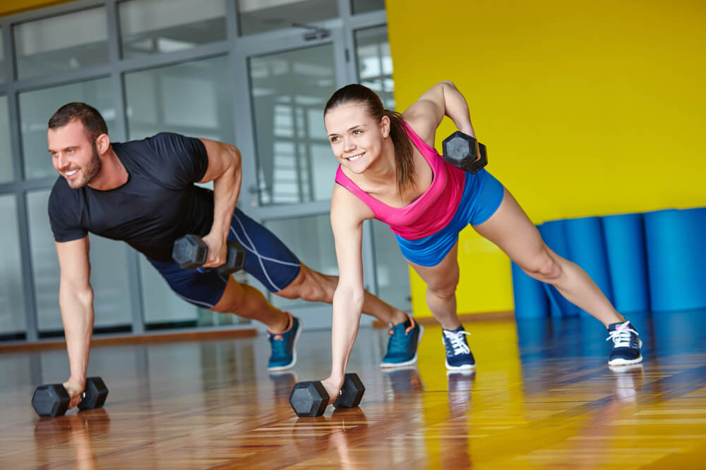 man and woman in plank position lifting a weight