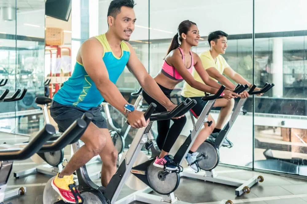 three people on exercise bikes in the gym