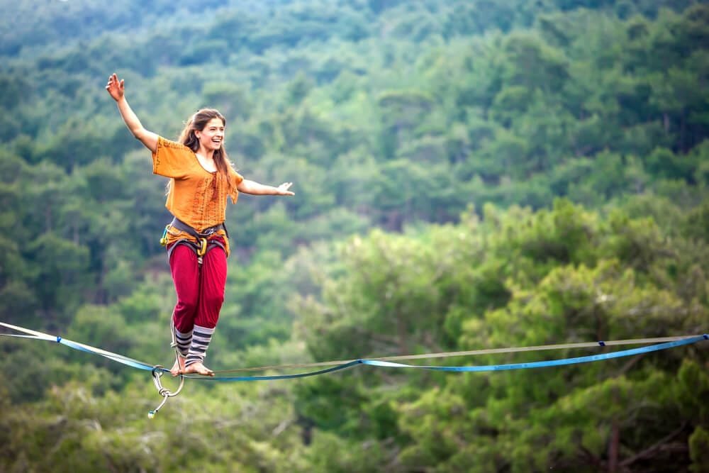 woman balancing on a slackline above the forest.