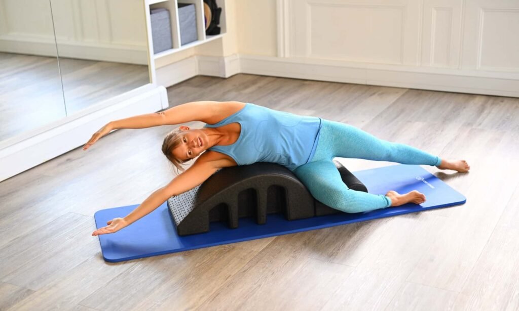 woman doing a side stretch on a pilates spine corrector 