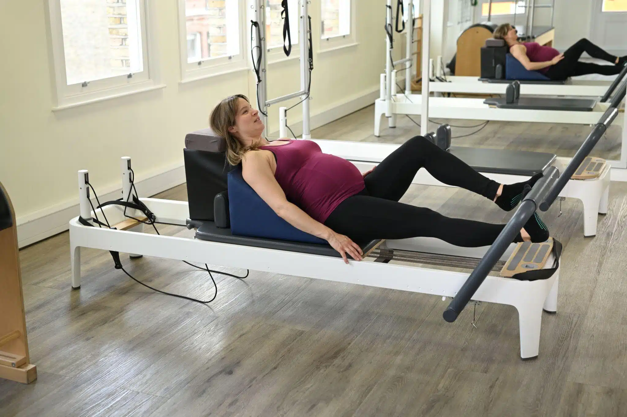 A pregnant woman performing an exercise on the Reformer with assistive specialised equipment